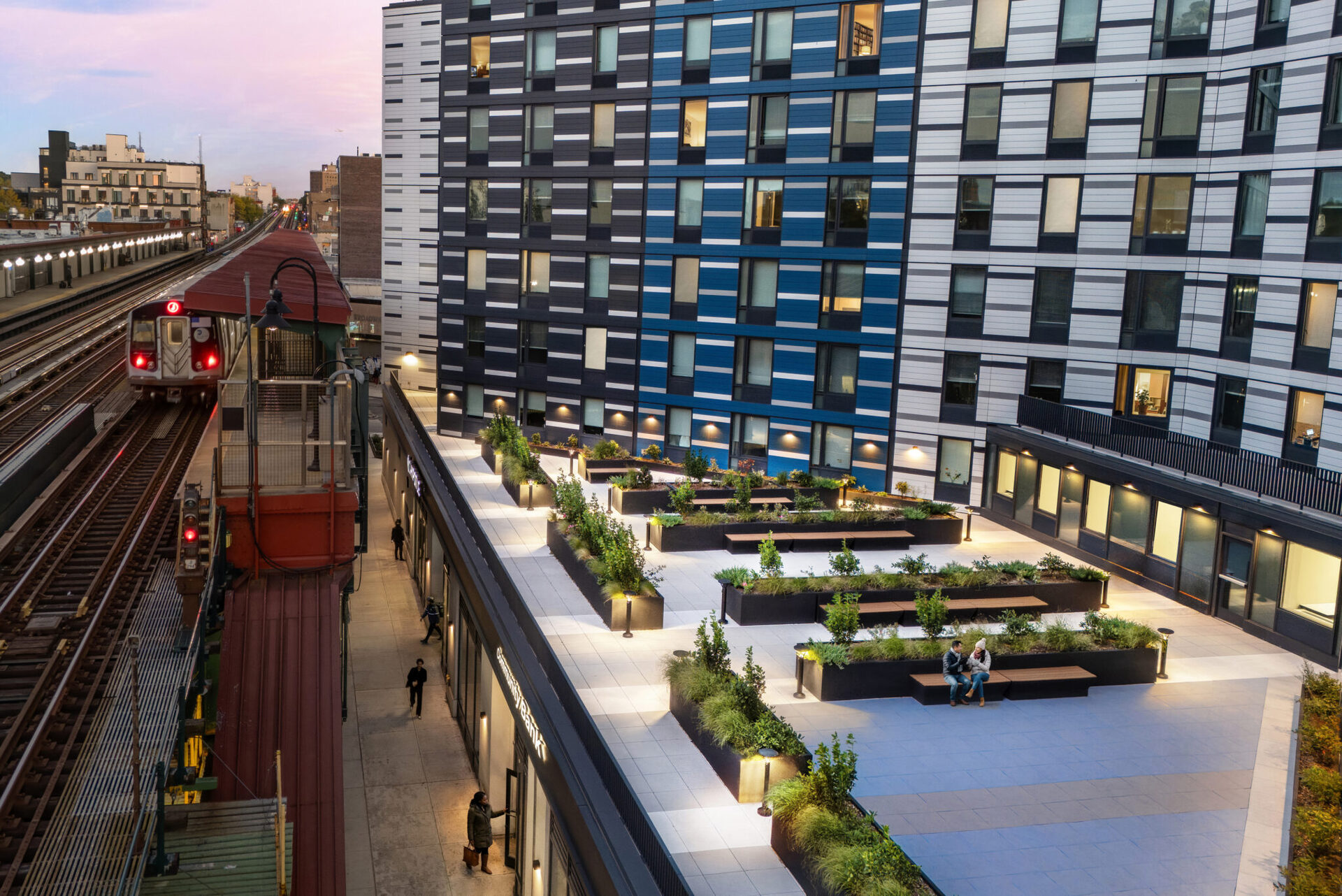1510 Broadway — rooftop amenity deck at dusk with elevated train passing in the foreground