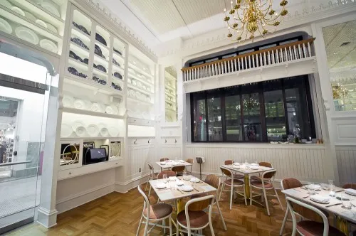 Caffè Storico — daytime corner view of the dining room with plate-wall, banquette seating, and statue framed in the museum window