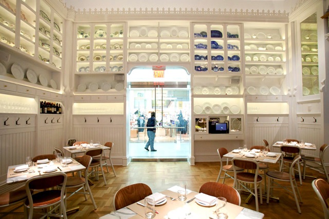 Caffè Storico — front of the dining room with plate-wall, herringbone floor, and view through the doorway into the New-York Historical Society lobby