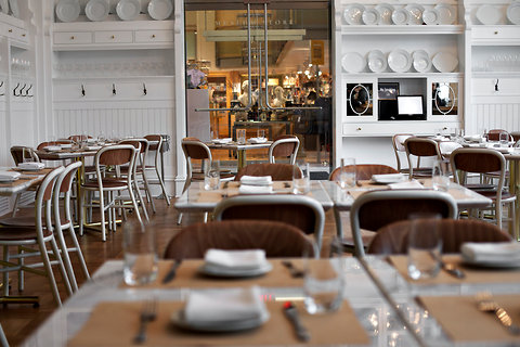 Caffè Storico — close view of set dining tables with the plate-wall and lobby pass beyond