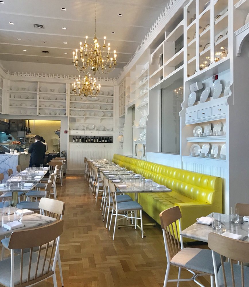 Caffè Storico — wide view of the dining room with full plate-wall, banquette seating, and open kitchen pass