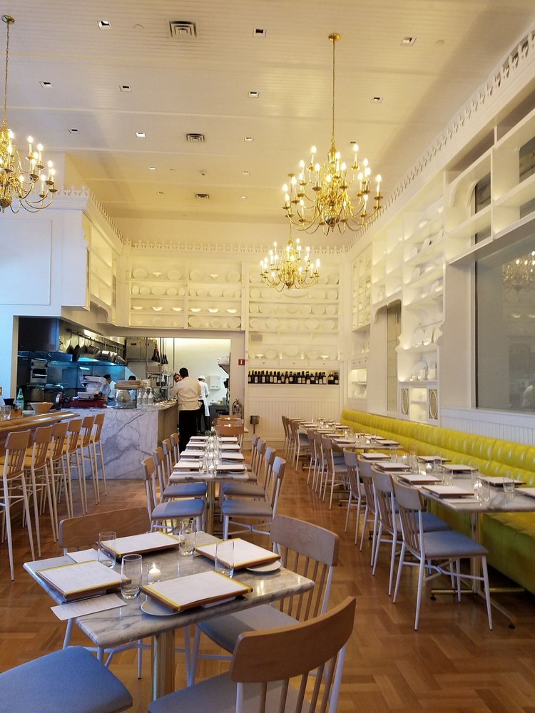 Caffè Storico — view toward the open kitchen pass beneath the brass chandeliers