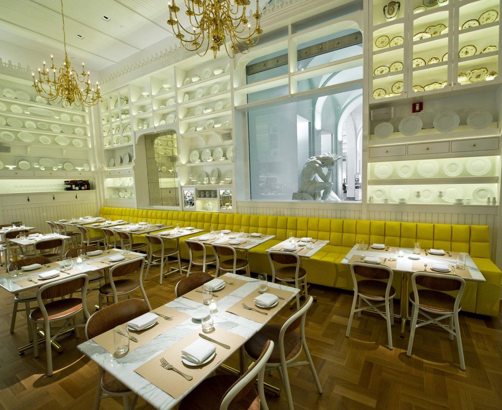 Caffè Storico — banquette and dining tables with the museum lobby statue framed in the glazed window