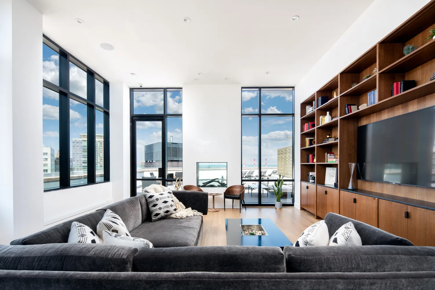 The Oriana — high-floor residence living room with library wall and Manhattan views