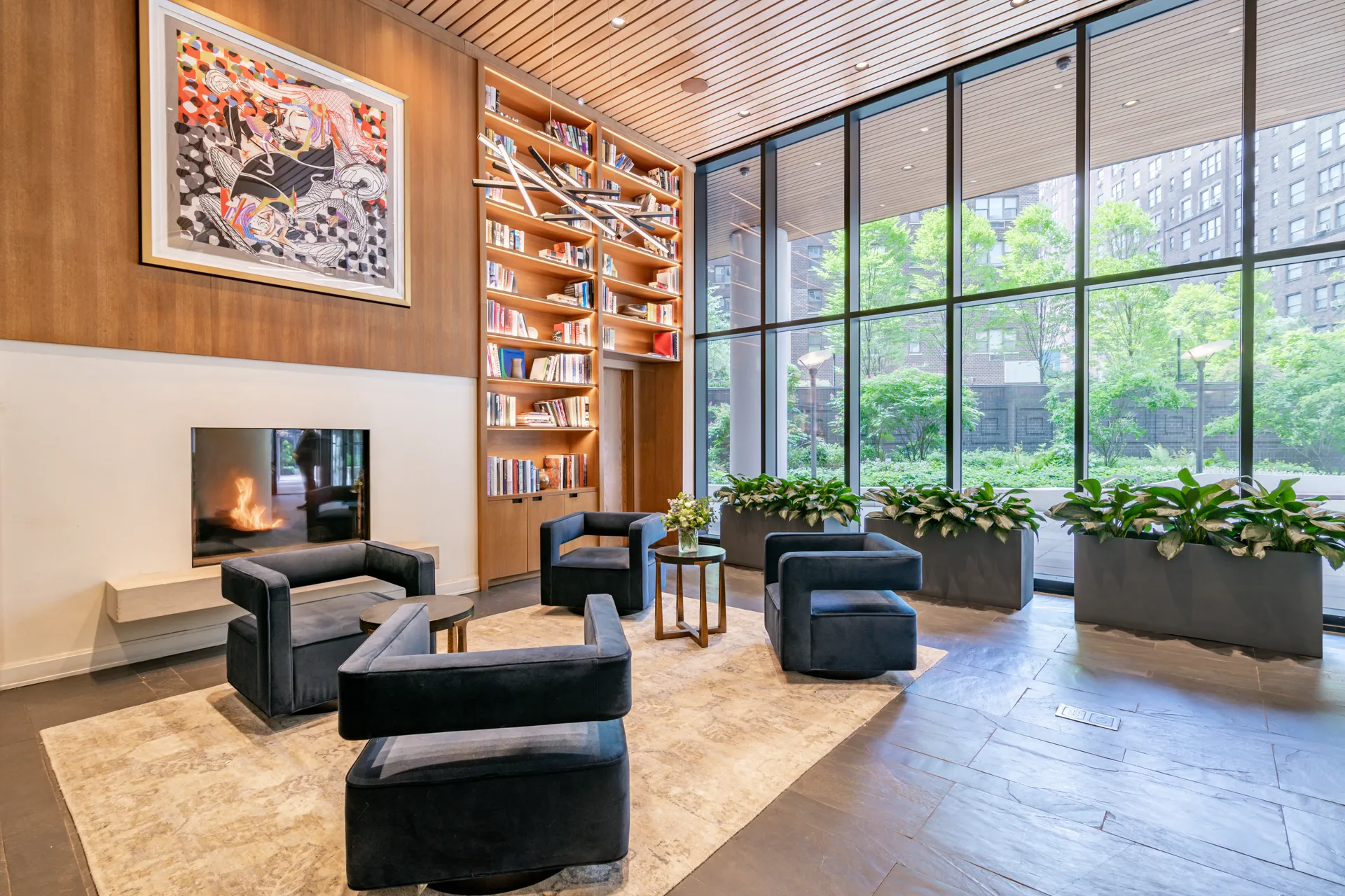 The Oriana — rooftop-level library lounge with fireplace, gallery wall, bookshelves, and floor-to-ceiling courtyard windows