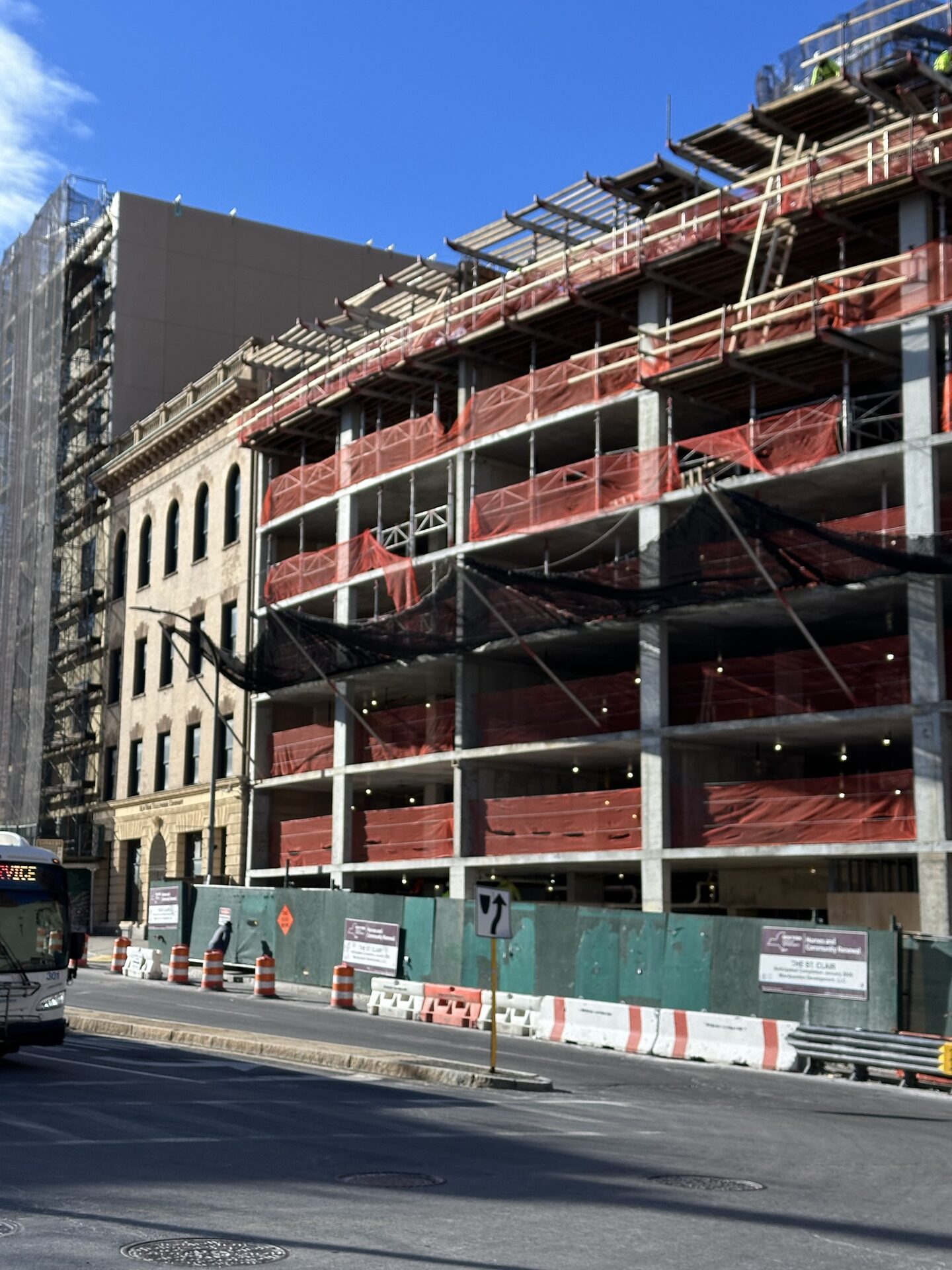 The St. Clair — exterior during construction, showing the new structural frame alongside the preserved historic stone-faced building next door