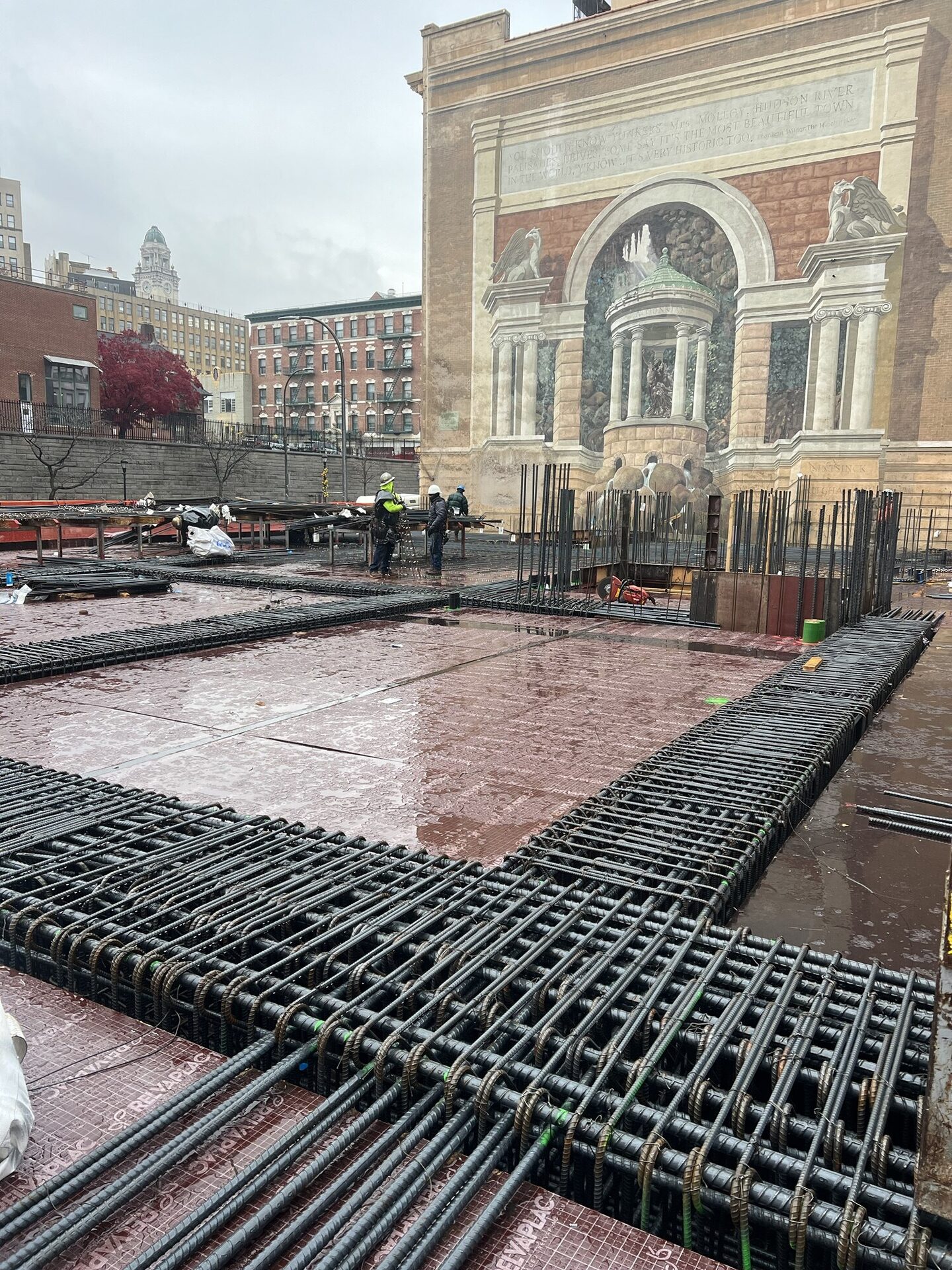 The St. Clair — rebar cages staged on the deck before a concrete pour, with historic stone facade visible behind